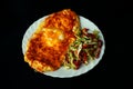 Salad of fresh vegetables and khachapurin on a white plate on a dark background. Close-up