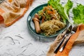 Salad of fresh vegetables on a plate with leaves, next to toasted pasta spaghetti with egg and meat sausage Royalty Free Stock Photo