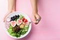 Salad with fruits and vegetables on plate holding by woman hand and eating