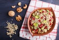 Salad of germinated buckwheat, avocado, walnut and pomegranate seeds in clay plate on black wooden background Royalty Free Stock Photo