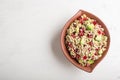 Salad of germinated buckwheat, avocado, walnut and pomegranate seeds in clay plate on white wooden background Royalty Free Stock Photo