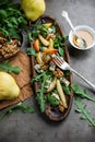 Salad with gorgonzola, rucola, pears, walnuts and honey in a long wooden plate.