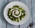 Salad with green beans and chicken eggs sauce on a white plate, plain table and fork