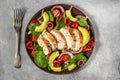 Salad with grilled chicken breast, avocado, spinach, cherry berries and tomato in a plate with fork. top view