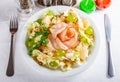 Salad with ham, iceberg, pear, grape and pumpkin seeds on white plate. Royalty Free Stock Photo