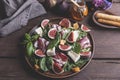 Salad with herbs, prosciutto, figs, cheese, honey on a plate. Wooden table