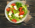 Salad with herbs, seasonal tomatoes on a wooden background