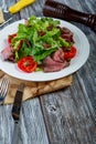 Salad leaves with sliced roast beef and sun-dried cherry tomatoes on wooden background Royalty Free Stock Photo