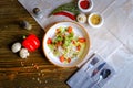 Salad with lettuce, cherry tomatoes, radish slices, herbs are served on a dark tabletop on a linen napkin. Hot red pepper and