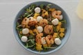 Salad with mango, mozzarella, shrimps and mixed microgreens in blue bowl on white oak table Royalty Free Stock Photo