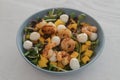 Salad with mango, mozzarella, shrimps and mixed microgreens in blue bowl on white oak table Royalty Free Stock Photo