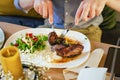 Salad with meat on a plate, on a wooden table. Male hands with a fork and knife, cuts meat. Royalty Free Stock Photo