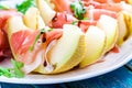 Salad of melon with thin slices of prosciutto, arugula leaves and balsamic sauce closeup