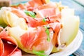 Salad of melon with thin slices of prosciutto, arugula leaves and balsamic sauce closeup