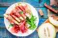 Salad of melon with thin slices of prosciutto, arugula leaves and balsamic sauce top view