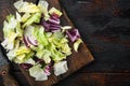 Salad with a mix of different salad leaves, like romaine lettuce, endive or arugula, on wooden cutting board, on old dark  wooden Royalty Free Stock Photo
