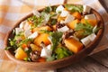 Salad with persimmon, arugula, oranges and cheese close-up