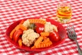 Salad of pickled vegetables cauliflower, paprika and carrot slices in a red plate and a glass of rakia grape, brandy like