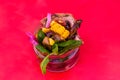 Salad with pieces of beef meat, grilled vegetables - eggplant, corn, mushrooms, sauce in a glass jar on a red background Royalty Free Stock Photo