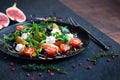 Salad on a plate: arugula, cherry tomatoes, figs, grated cheese, black grapes, avocado Royalty Free Stock Photo