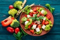 Salad in a plate. Feta cheese, cherry tomatoes, paprika, lettuce. Healthy food. On a blue wooden table table. Royalty Free Stock Photo
