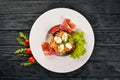 Salad with prosciutto, quail eggs, prunes and fresh vegetables on the plate. On a wooden background. Top view. Royalty Free Stock Photo