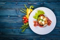 Salad with prosciutto, quail eggs, prunes and fresh vegetables on the plate. On a wooden background. Top view. Royalty Free Stock Photo