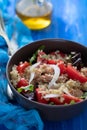 Salad quinoa with tuna, tomato and lettuce in blue bowl on wooden background