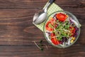 Salad with red cabbage, radish sprouts, corn and tomatoes on wooden background with copy space