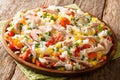 Salad of rice, tuna, tomatoes, sweet pepper, corn, green peas and herbs close-up in a plate. horizontal