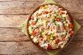 Salad of rice, tuna, tomatoes, sweet pepper, corn, green peas and herbs close-up in a plate. horizontal top view