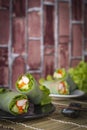 Salad rolls on black plate placed on a wood sieve there is chopsticks placed beside and Salad rolls on white plate placed backside