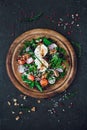 Salad on a round wooden cutting board. Ingredients: soft-boiled egg, radish, cherry tomatoes, greens, red onions, arugula, dill, Royalty Free Stock Photo