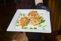 Salad with salmon, peas and mayonnaise. Salad Olivier served on a white plate by waiter in restaurant or diner