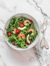 Salad with shrimp, arugula,avocado, cherry tomatoes on a light marble background, top view Royalty Free Stock Photo