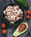 Salad with shrimp, avocado and tomato sauce in a black dish.