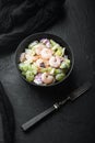 Salad with shrimp, avocado, tomatoes and mayonnaise on the lettuce , with sauce apple and grape, on black stone background, top