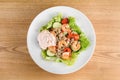 Salad with shrimps, quinoa, tomatoes, peppers, cucumber, lettuce, mayonnaise on white round plate on wooden table Royalty Free Stock Photo