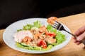Salad with shrimps, quinoa, tomatoes, peppers, cucumber, lettuce, mayonnaise on white round plate on wooden table Royalty Free Stock Photo