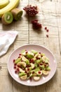 Salad of slices of various fruits and pomegranate seeds on a wooden background