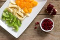 Salad of slices of various fruits and pomegranate seeds on a wooden background