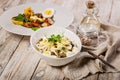 Salad with squid rings, mozzarella cheese, olives, capers and microgreens and baked vegetables with mushrooms in a white bowl. Royalty Free Stock Photo