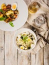 Salad with squid rings, mozzarella cheese, olives, capers and microgreens and baked vegetables with mushrooms in a white bowl. Royalty Free Stock Photo