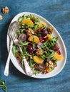 Salad with tangerines, grapes, arugula, pomegranate and walnuts with a honey dressing on a blue background