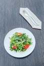 Salad with tomatoes, arugula, sunflower seeds and herbs on white ceramic plate over rustic wood background Royalty Free Stock Photo