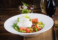 Salad with tomatoes and burrata cheese with lettuce and olive oil on wooden background. Royalty Free Stock Photo