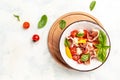 Salad with tomatoes, cream cheese balls, prosciutto and basil leaves on light background. Detox and healthy superfoods bowl Royalty Free Stock Photo