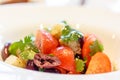 Salad with tomatoes, olives and parsley is on the plate.