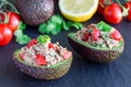 Salad with tuna, avocado, tomatos, coriander and lemon juice served in avocado bowls, ingredients on background, horizontal Royalty Free Stock Photo