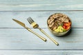 A salad with various kinds of diced tomato, avocado and lots of canned tuna in a golden bowl and matching cutlery